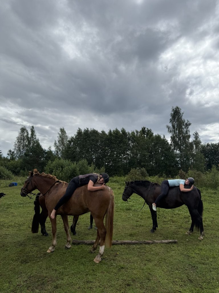 Ratsanikud lamavad hobuste seljas karjamaal